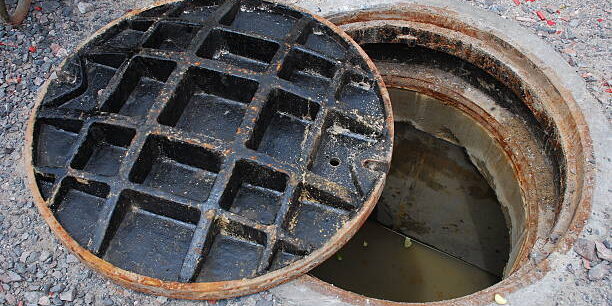 Partially open manhole on a street with water/sewage visible below marmaraereğlisi rögar açma